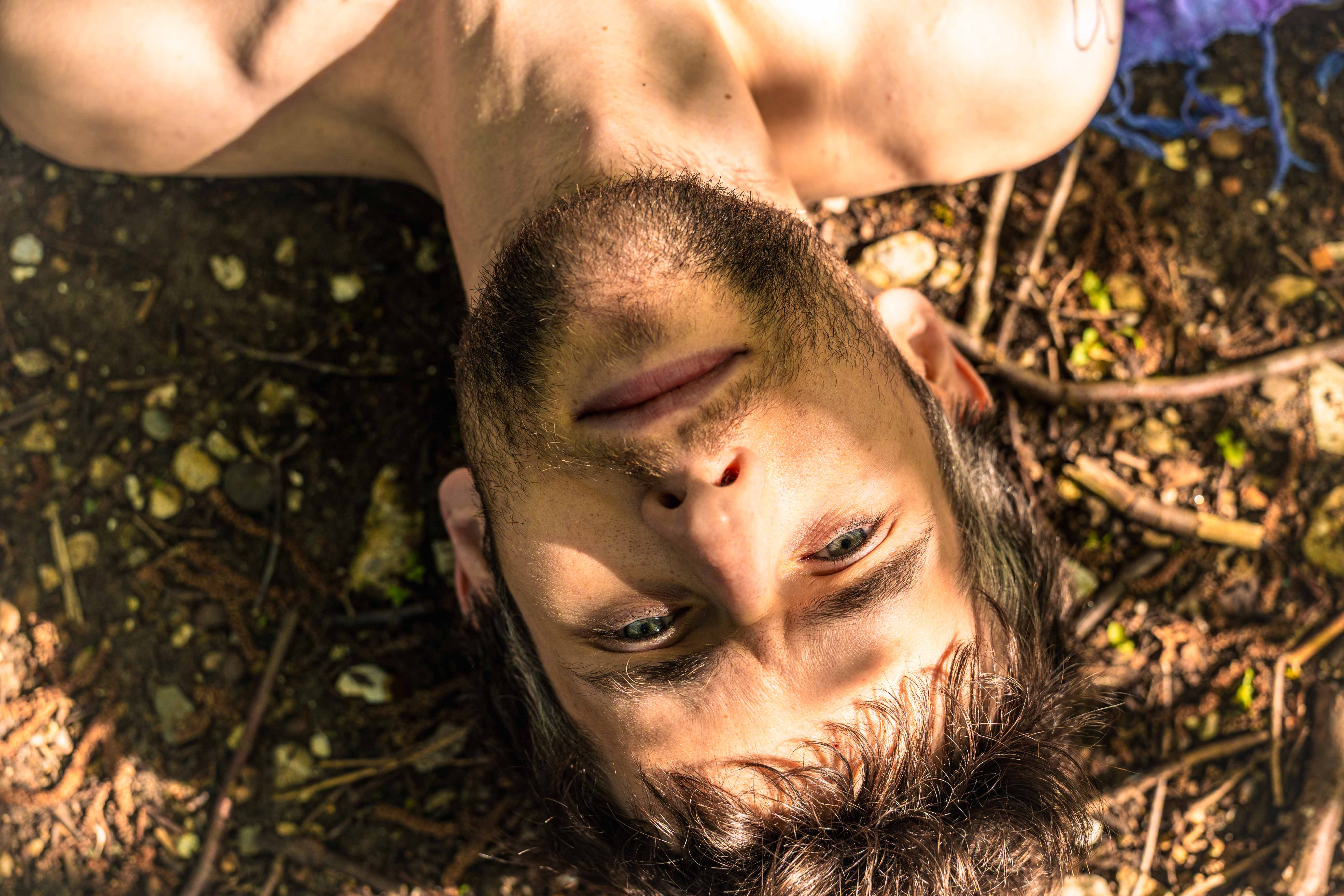 A photo of a man's face, upside down. He is looking at the camera.